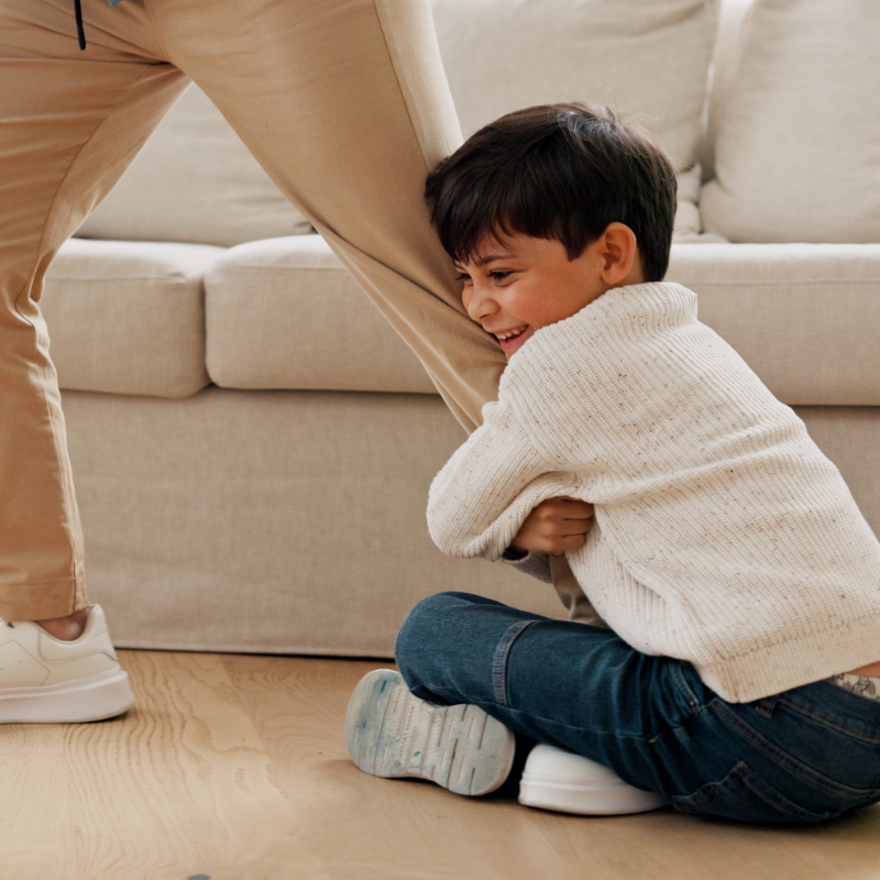 Child clinging on to father's leg as a babysitter is arriving